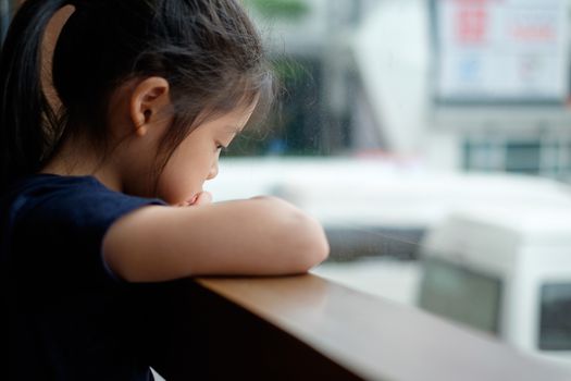 Abandoned sad and lonely Asian child sits next to window.