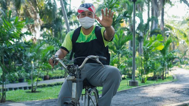 Asian male workers wear masks to prevent and stop infection Virus. Biking in a public garden makes the body immune to disease.