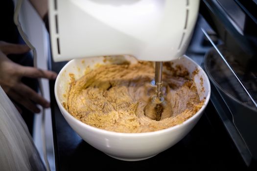 Mixer is mixing cookie ingredients in bowl.
