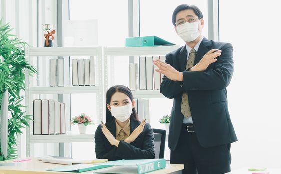 A team of Asian businessmen wear masks to protect and prepare to fight the pandemic virus worldwide. A team of Asian businessmen wearing black suits are working together in the office.