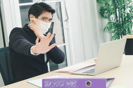 Asian business men wear masks to protect and prepare to fight the pandemic virus worldwide. An Asian business man wearing a black uniform working in an office.