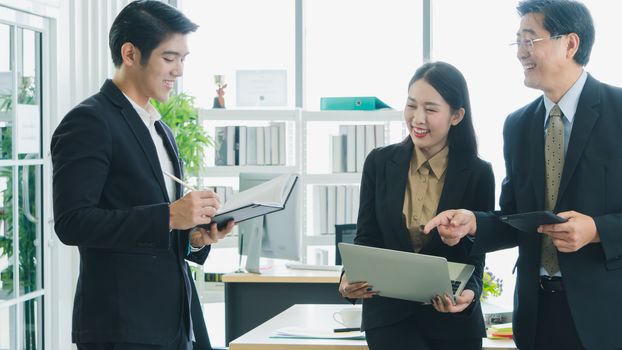 The Asian business team is working together happily at the office. Senior male business men are teaching a new generation of business people