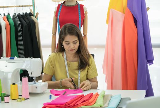 An Asian female fashion designer is working and smiling happily. Small businesses work from home.