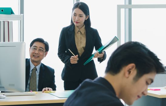 The Asian business team is working together happily at the office. Senior male business men are teaching a new generation of business people