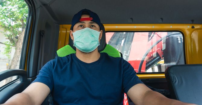 Close-up photos of Asian truck drivers wearing masks to protect against dust and the spread of the flu. Covid 19. Inside the car front