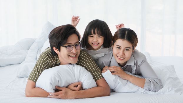 Photos of warm and lovely Asian families. Parents are playing happily and happily with their little daughter in the bedroom. Being happy to be with family on holidays