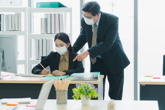 A team of Asian businessmen wear masks to protect and prepare to fight the pandemic virus worldwide. A team of Asian businessmen wearing black suits are working together in the office.