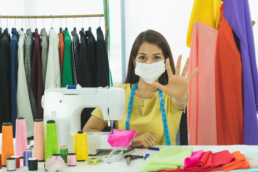 An Asian designer and tailor is working in the room. She wears a mask to protect against dust and prevent infection. From the outbreak of the corona virus That is currently spread throughout the world