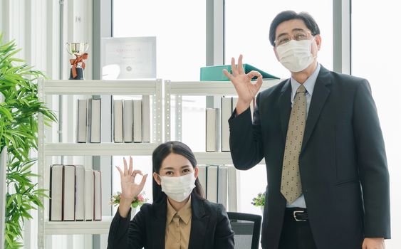 A team of Asian businessmen wear masks to protect and prepare to fight the pandemic virus worldwide. A team of Asian businessmen wearing black suits are working together in the office.