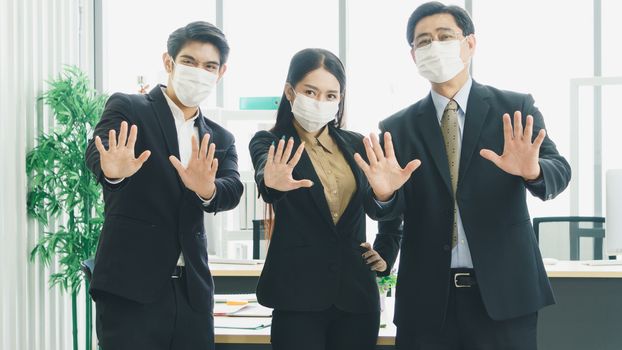 A team of Asian businessmen wear masks to protect and prepare to fight the pandemic virus worldwide. A team of Asian businessmen wearing black suits are working together in the office.
