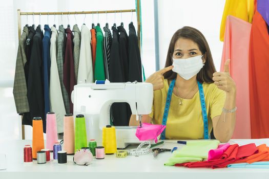 An Asian designer and tailor is working in the room. She wears a mask to protect against dust and prevent infection. From the outbreak of the corona virus That is currently spread throughout the world