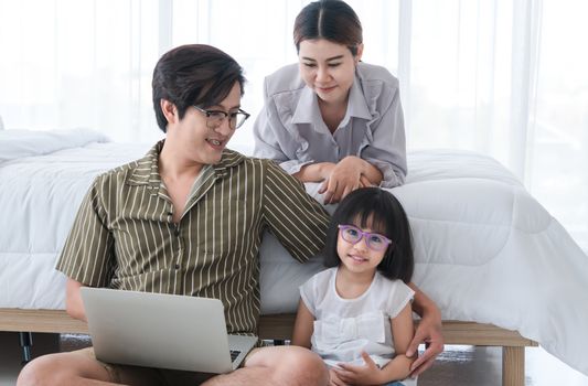 Photos of warm and lovely Asian families. Parents are playing happily and happily with their little daughter in the bedroom. Being happy to be with family on holidays