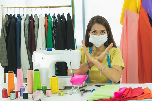 An Asian designer and tailor is working in the room. She wears a mask to protect against dust and prevent infection. From the outbreak of the corona virus That is currently spread throughout the world