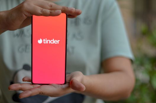 New Delhi, India, 2020. Girl holding mobile with Tinder logo on smartphone screen in female hands. Tinder is a social search and dating mobile app