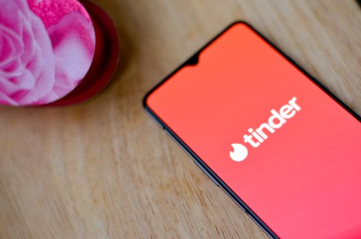 New York, USA, 2020. Flat lay with Tinder app logo on a smartphone screen with a pink heart on a wooden background on display. Tinder is an online social search and dating mobile phone app