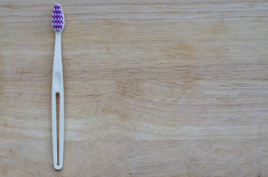 White or cream colored bamboo toothbrush on wood background. Zero waste, biodegradable material, concept - Save the environment