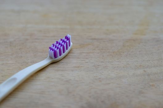 White or cream colored bamboo toothbrush on wood background. Zero waste, biodegradable material, concept - Save the environment