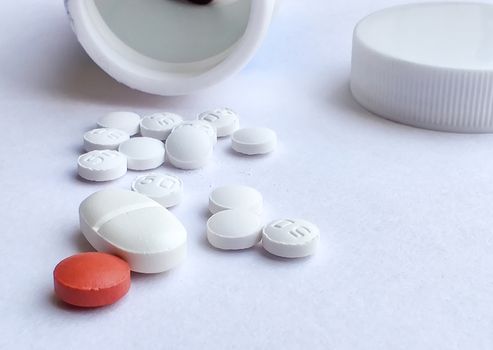 Pills spilling out of a plastic bottle and isolated on white background. Top view with copy space. Medicine concept