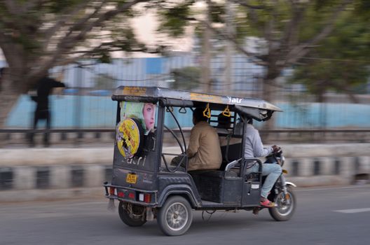 Delhi, India, 2020.Panning shot of a speeding e- rickshaw on Delhi roads. Electric rickshaws are economical mode of transportation in India for last mile travel. Battery capacity increasing gradually.