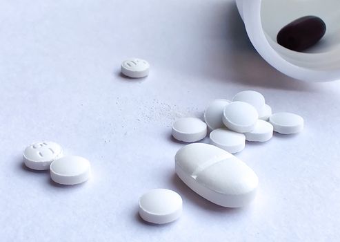 Pills spilling out of a plastic bottle and isolated on white background. Top view with copy space. Medicine concept