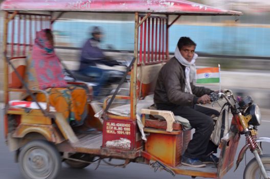 Delhi, India, 2020.Panning shot of a speeding e- rickshaw on Delhi roads. Electric rickshaws are economical mode of transportation in India for last mile travel. Battery capacity increasing gradually.
