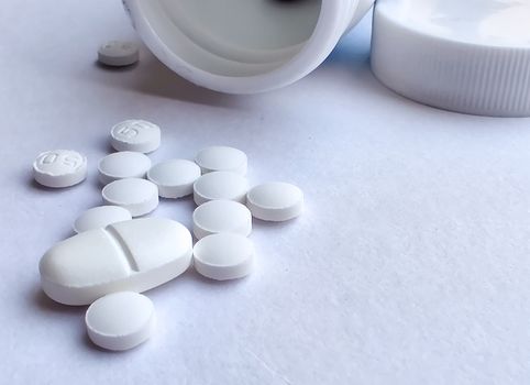 Pills spilling out of a plastic bottle and isolated on white background. Top view with copy space. Medicine concept