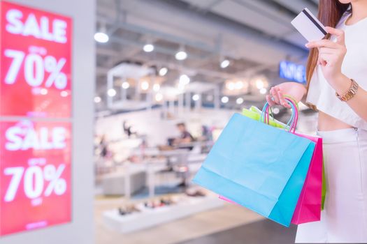 Woman with shopping bags and credit card  in shopping mall, consumerism and sale concept.