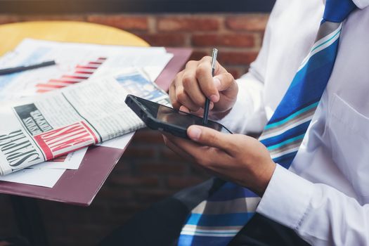 A handsome businessman reading a text from a mobile phone while sitting in a coffee shop.