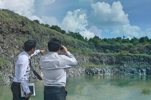 Look. The handsome man is looking at binoculars to the target.