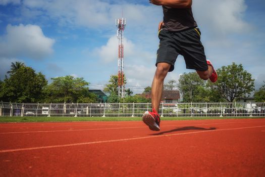 Young man jogging in the morning sun in the stadium.