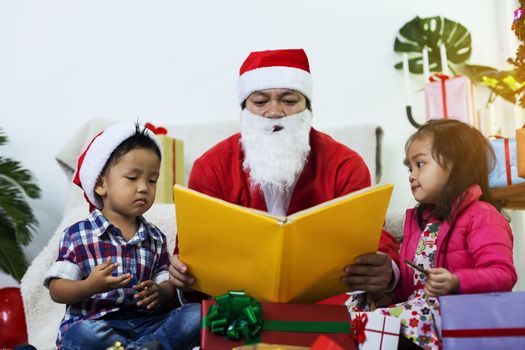 Santa Claus gives gifts and reads fairy tales to boys and girls listening in the festive season.