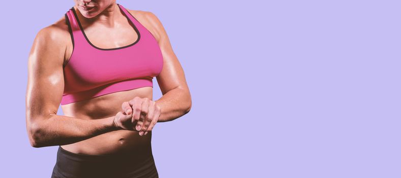 Muscular woman flexing her arm against purple background