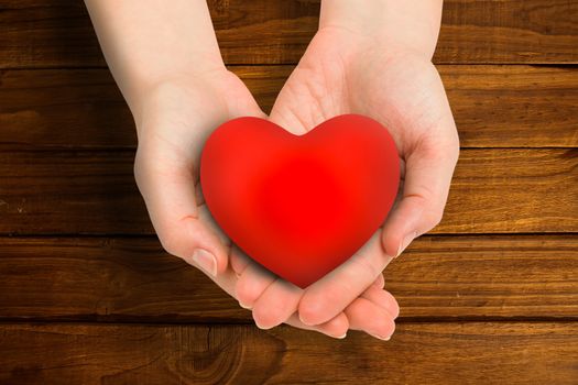 Hand showing heart against overhead of wooden planks