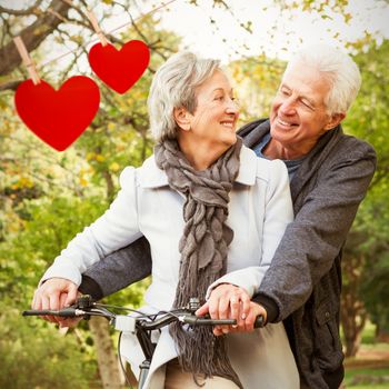 Senior couple in the park against hearts hanging on a line