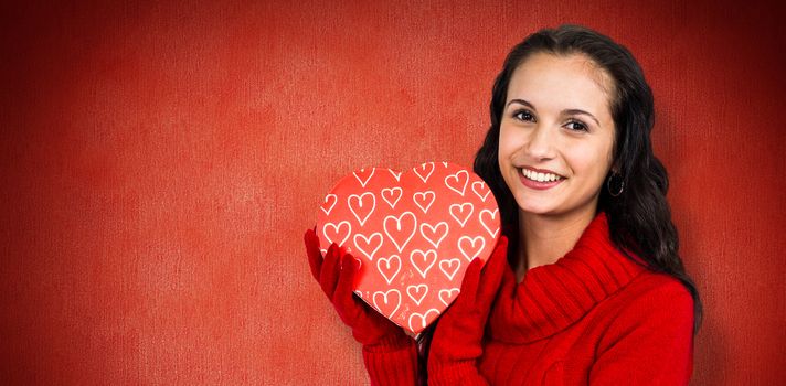 Smiling woman holding gift box against red background