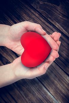 Hand showing heart against wooden background