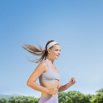 Sporty smiling blonde jogging  against park on sunny day