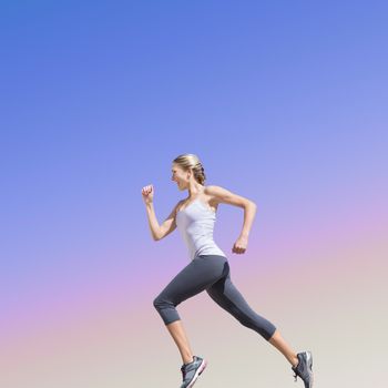 Pretty fit blonde jogging  against purple sky