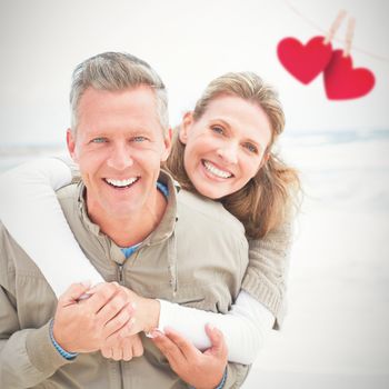 Smiling couple holding one another against hearts hanging on a line