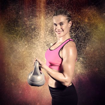 Muscular woman lifting heavy kettlebell against dark background