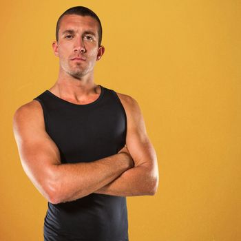 Confident athlete with arms crossed against orange background