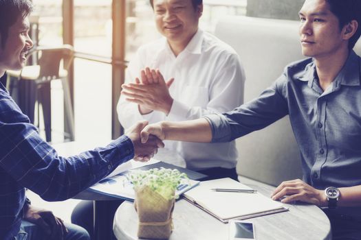 Businessmen negotiate in a coffee shop. Hold hands and greet before the business talks comfortably.