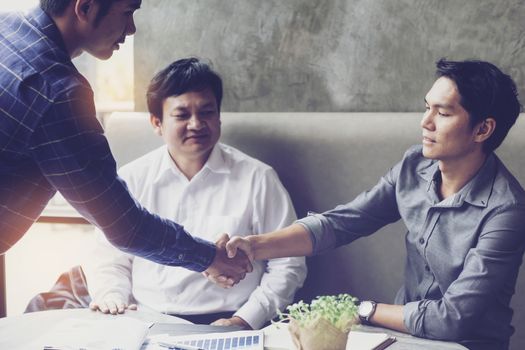 Businessmen negotiate in a coffee shop. Hold hands and greet before the business talks comfortably.