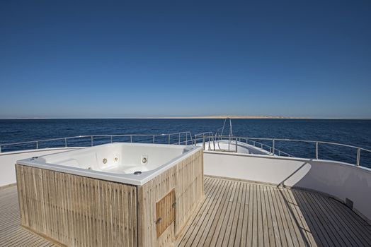 View over the bow of a large luxury motor yacht on tropical open ocean with hot tub