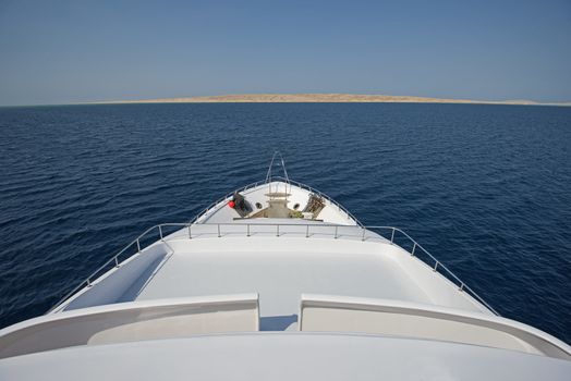 View over the bow of a large luxury motor yacht on tropical open ocean