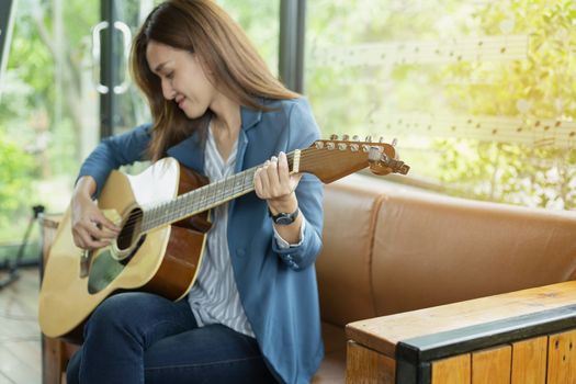 Beautiful girl is playing guitar by the window. Education lifestyle relax concept