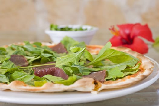 Meat pizza with a green salad topping