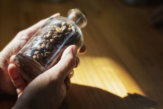 Close-up image of hand holding coffee beans in glass bottles