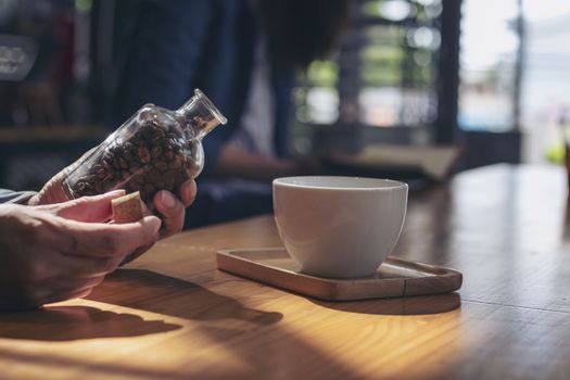 Close-up image of hand holding coffee beans in glass bottles