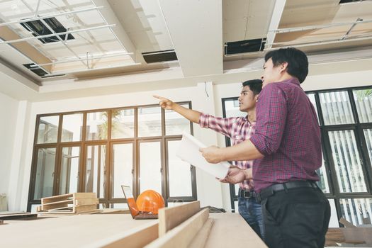 Two engineers are working on a blueprint. With work space